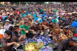 Sejumlah warga menyantap nasi Tumpeng dan 'Ingkung' ayam bersama saat tasyakuran 'Wiwit Mbako, Panen Kopi' di alun-alun Temanggung, Jawa Tengah, Minggu (21/8/2022). Ribuan petani tembakau dan petani kopi melakukan tasyakuran dan doa bersama sebagai permohonan kepada Tuhan YME agar panen tembakau dan kopi tahun ini mendapat hasil yang memuaskan. ANTARA FOTO/Anis Efizudin/nym.