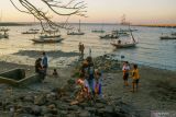 Sejumlah anak bermain di sekitar perahu nalayan yang ditambatkan di  bawah Jembatan Suramadu, Surabaya, Jawa Timur, Senin (22/8/2022). Kawasan tersebut ramai dikunjugi warga untuk berwisata khususnya di saat air laut surut. ANTARA Jatim/Hildaniar Novitasari/zk