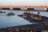 Sejumlah anak bermain di sekitar perahu nalayan yang ditambatkan di  bawah Jembatan Suramadu, Surabaya, Jawa Timur, Senin (22/8/2022). Kawasan tersebut ramai dikunjugi warga untuk berwisata khususnya di saat air laut surut. ANTARA Jatim/Hildaniar Novitasari/zk