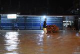 Sejumlah warga berjalan melintasi banjir yang merendam Rumah Sakit Umum Daerah dr Abdul Aziz di Jalan dr Sutomo, Kelurahan Pasiran, Kota Singkawang, Kalimantan Barat, Sabtu (27/8/2022) malam. Banjir menggenangi sejumlah ruas jalan, pemukiman penduduk dan fasilitas umum di Kota Singkawang akibat tingginya curah hujan sejak Sabtu (27/8/2022) siang hingga malam hari di wilayah setempat.ANTARA FOTO/Reza Novriandi/jhw