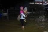 SINGKAWANG TERENDAM BANJIR AKIBAT HUJAN. Seorang warga menggendong anak saat berjalan melintasi banjir di Jalan dr Sutomo, Kelurahan Pasiran, Kota Singkawang, Kalimantan Barat, Sabtu (27/8/2022) malam. Banjir menggenangi sejumlah ruas jalan, pemukiman penduduk dan fasilitas umum di Kota Singkawang akibat tingginya curah hujan sejak Sabtu (27/8/2022) siang hingga malam hari di wilayah setempat. ANTARA FOTO/Reza Novriandi/jhw