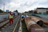 Pekerja melintas di samping proyek pembangunan jalur kereta api (KA) layang Medan-Binjai di Jalan Sekip, Medan, Sumatera Utara, Selasa (30/8/2022). Pembangunan jalur kereta api layang yang masuk dalam salah satu prioritas kegiatan Kementerian Perhubungan Tahun Angggaran 2022 sepanjang 6,8 kilometer tersebut ditargetkan selesai pada 2024. ANTARA FOTO/Fransisco Carolio