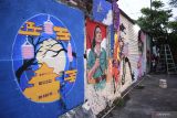 Seorang mahasiswa membuat mural di kampung pecinan Tambak Bayan, Surabaya, Jawa Timur, Jumat (2/9/2022). Kegiatan 