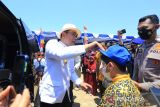 Gubernur Jawa Barat Ridwan Kamil (kiri) memasangkan topi kepada seorang anak saat melakukan bakti sosial di Kampung nelayan Karangsong, Indramayu, Jawa Barat, Kamis (15/9/2022). Polda Jabar bersama Pemprov Jawa Barat memberikan paket bantuan sembako kepada 2.000 nelayan di wilayah pesisir Pantura yang terdampak kenaikan harga BBM subsidi. ANTARA FOTO/Dedhez Anggara/agr
