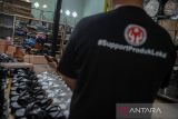 Pekerja menyelesaikan produksi alas kaki di rumah produksi 