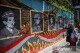 Ibu menunjukan kepada anaknya Pahlawan Revolusi yang gugur pada peristiwa Gerakan 30 September (G30S) di Cimindi, Cimahi, Jawa Barat, Selasa (27/9/2022). Mural yang digambar oleh muralis dari komunitas Seniman Kreatif Cimindi tersebut bertujuan untuk mengedukasi masyarakat khususnya anak-anak untuk mengenal Pahlawan Revolusi yang gugur pada peristiwa G30S. ANTARA FOTO/Raisan Al Farisi/agr