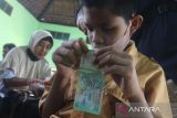 Seorang penyandang tuna netra meraba uang rupiah saat sosialisasi keaslian uang rupiah di Balai Desa Ngebrak, Kediri, Jawa Timur, Sabtu (1/10/2022). Bank Indonesia kantor perwakilan Kediri melakukan sosialisasi ciri-ciri keaslian uang rupiah tahun emisi 2022 kepada difabel hingga tingkat desa. ANTARA Jatim/Prasetia Fauzani/zk