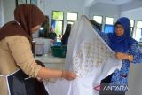 Guru bersama murid mempersiapkan kain batik untuk proses pewarnaan saat praktek belajar membatik di Sekolah Menengah Negeri-I Lhoknga, Kabupaten Aceh Besar, Aceh, Sabtu (1/10/2022). Pembelajaran membatik kepada murid di sekolah itu dalam rangka menyambut Hari Batik Nasional yang  bertujuan memberikan edukiasi kepada pelajar mencintai dan melestarikan batik sebagai kekayaan budaya nasional.ANTARA FOTO/Ampelsa.