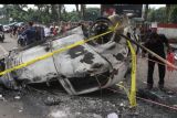 Seorang warga melintas di samping mobil yang terbakar pasca kerusuhan di Stadion Kanjuruhan, Malang, Jawa Timur, Minggu (2/10/2022). Polda Jatim mencatat data sementara korban jiwa dalam kejadian tersebut berjumlah 127 orang dan 13 kendaraan rusak. ANTARA FOTO/Ari Bowo Sucipto/nym.