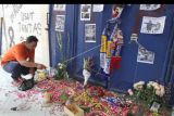 Seorang suporter Arema FC (Aremania) menaburkan bunga di depan pintu tribun 13 Stadion Kanjuruhan, Malang, Jawa Timur, Selasa (4/10/2022). Menurut sejumlah saksi mata korban terbanyak dalam tragedi Kanjuruhan berada di pintu tribun 11, 12, dan 13 yang saat kejadian pintu keluar tersebut terkunci sehingga penonton yang menghindari gas air mata tidak dapat keluar. ANTARA FOTO/Ari Bowo Sucipto/nym.