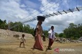 Warga bersama anaknya menyeberangi sungai di lokasi pembangunan jembatan gantung kawasan pedalaman Desa Siron, Kecamatan Kuta Cot Glie, kabupaten Aceh Besar, Aceh, Selasa (4/10/2022). Kementerian Pekerjan Umum dan Perumahan Rakyat (PUPR) tahun 2022 membangun empat jembatan gantung dengan anggaran sebesar Rp12.8 miliar menggantikan jembatan lama yang rusak di sejumlah daerah pedalaman di provinsi Aceh untuk meningkatkan koneksitas antar desa dan akses ke sekolah di daerah itu, ANTARA FOTO/Ampelsa.