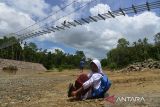 Anak sekolah memakai sepatunya seusai menyeberangi sungai di lokasi pembangunan jembatan gantung kawasan pedalaman Desa Siron, Kecamatan Kuta Cot Glie, kabupaten Aceh Besar, Aceh, Selasa (4/10/2022). Kementerian Pekerjan Umum dan Perumahan Rakyat (PUPR) tahun 2022 membangun empat jembatan gantung dengan anggaran sebesar Rp12.8 miliar menggantikan jembatan lama yang rusak di sejumlah daerah pedalaman di provinsi Aceh untuk meningkatkan koneksitas antar desa dan akses ke sekolah di daerah itu, ANTARA FOTO/Ampelsa.