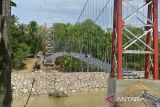 Pekerja menyelesaikan pembangunan jembatan gantung menggantikan jembatan lama yang rusak diterjang banjir tahun 2018 di kawasan pedalaman Desa Siron, Kecamatan Kuta Cot Glie, kabupaten Aceh Besar, Aceh, Selasa (4/10/2022). Kementerian Pekerjan Umum dan Perumahan Rakyat (PUPR) pada tahun 2022 membangun empat jembatan gantung dengan anggaran sebesar Rp12.8 miliar di Aceh untuk meningkatkan koneksitas antar desa dan akses warga, anak sekolah dan perekonomian masyarakat. ANTARA FOTO/Ampelsa.