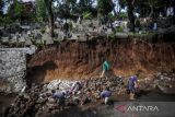 Petugas memeriksa kawasan pemakaman umum yang terdampak longsor di TPU Sirnaraga, Bandung, Jawa Barat, Rabu (5/10/2022). Hujan deras pada Selasa (5/10/2022) membuat sebagian pemakaman di TPU Sirnaraga longsor dan membuat sejumlah warga memindahkan jenazah yang masih utuh ke tempat yang lebih layak. ANTARA FOTO/Raisan Al Farisi/agr