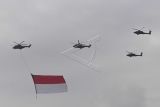 Helikopter Tri Matra Flight membawa bendera Merah Putih saat fly pass perayaan HUT ke-77 TNI di Langit Monas, Jakarta, Rabu (5/10/2022). Perayaan HUT ke-77 TNI mengangkat tema 'TNI Adalah Kita' menampilkan fly pass pesawat tempur F-16, atraksi Jupiter Aerobatic Team dan helikopter Tri Matra Flight membawa bendera merah putih. ANTARA FOTO/Wahyu Putro A/nym.