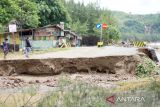 warga berjalan di akses jalan yang terputus akibat erosi banjir di Pantai Gemah, Tulungagung, Jawa Timur, Selasa (11/10/2022). Obyek wisata unggulan di pesisir selatan Tulungagung bagian barat ini rusak parah terdampak banjir bandang yang terjadi pada Minggu (9/10/2022) malam. ANTARA Jatim/Destyan Sujarwoko/zk 