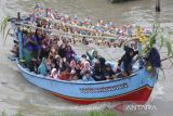 Warga menaiki perahu yang di hias dengan bendera, buah dan minuman botol di sungai Cimanuk, Indramayu, Jawa Barat, Rabu (19/10/2022). Tradisi yang digelar nelayan udang itu sebagai ungkapan rasa syukur atas hasil tangkapan udang yang melimpah dan keselamatan ketika melaut dengan ritual melarung kepala kerbau ketengah laut sebagai sesajen. ANTARA FOTO/Dedhez Anggara/agr