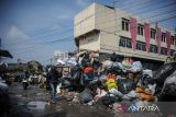 Warga melintas di samping sampah yang menumpuk di Pungkur, Bandung, Jawa Barat, Kamis (20/10/2022). Penumpukan sampah tersebut terjadi akibat akses jalan menuju TPA Sarimukti yang licin dan berlumpur sehingga menyebabkan operasional truk sampah dari berbagai wilayah di Bandung Raya mengalami keterlambatan. ANTARA FOTO/Raisan Al Farisi/agr