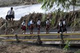 Sejumlah siswa menyeberangi sungai saat berangkat ke sekolah pascabanjir bandang di Dusun Sekar Kejula Kelod, Desa Yehembang Kauh, Jembrana, Bali, Selasa (25/10/2022). Sejak jembatan beton penghubung empat dusun yakni Dusun Sekar Kejula Kelod, Dusun Sekar Kejula, Dusun Kedisan, dan Dusun Munduk Anggrek tersebut ambruk akibat diterjang banjir bandang yang terjadi pada Minggu (16/10) lalu, banyak siswa dan warga memilih menyeberang sungai dengan berjalan kaki saat menuju sekolah maupun kantor desa menyusul jauhnya jarak jalur alternatif di dusun itu. ANTARA FOTO/Nyoman Hendra Wibowo/hp.