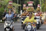Sejumlah perempuan mengendarai sepeda motor sambil membawa gebogan atau sesajen berisi buah, bunga dan hiasan janur saat parade kebaya dalam kampanye mendukung Gerakan Kebaya Goes to UNESCO di Desa Bongkasa, Badung, Bali, Jumat (28/10/2022). Kegiatan yang bertajuk 'Lenggang Bali Pertiwi' tersebut digelar untuk melestarikan kebaya yang merupakan warisan luhur asli dari Indonesia agar bisa diajukan sebagai Warisan Budaya Tak Benda (Intangible Cultural Heritage) ke UNESCO sekaligus memperingati Hari Sumpah Pemuda. ANTARA FOTO/Nyoman Hendra Wibowo/nym.