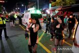 Pengunjung pesta berjalan di dekat ambulans di lokasi di mana puluhan orang terluka dalam penyerbuan selama festival Halloween di Seoul, Korea Selatan, (30/10/2022). Hingga Minggu (30/10) dini hari, pihak berwenang setempat menyatakan 146 orang meninggal dunia dan 150 orang lainnya luka-luka pada insiden tersebut. ANTARA FOTO/REUTERS/Kim Hong-ji/aww.