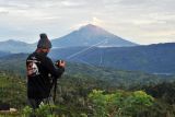 Fotografer bersiap memotret Gunung Kerinci yang sedang mengembuskan gas dan material ke udara yang terlihat dari Desa Belui, Depati Tujuh, Kerinci, Jambi, Jumat (4/11/2022). Gunung dengan ketinggian 3.805 mdpl yang masih berada pada level II (waspada) itu kembali mengalami gempa embusan yang terpantau secara visual pada Jumat pagi. ANTARA FOTO/Wahdi Septiawan/foc.
