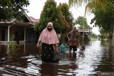 BANJIR LANDA KOTA SINGKAWANG. Empat warga berjalan melintasi pemukiman yang terendam banjir di Kota Singkawang, Kalimantan Barat, Minggu (6/11/2022). Banjir setinggi 10 cm hingga 90 cm menggenangi sejumlah ruas jalan, pemukiman penduduk dan fasilitas umum di Kota Singkawang akibat tingginya curah hujan sejak Sabtu (5/11/2022) malam hingga Minggu (6/11/2022) di wilayah setempat. ANTARA FOTO/Reza Novriandi/jhwANTARA FOTO/REZA NOVRIANDI (ANTARA FOTO/REZA NOVRIANDI)