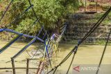 Warga melintasi jembatan rusak di Dusun Gunungsari, Desa Ciparay, Kecamatan Cidolog, Kabupaten Ciamis, Jawa Barat, Senin (14/11/2022). Jembatan gantung yang dibangun tujuh tahun lalu tersebut rusak akibat diterjang banjir bandang dan ratusan warga di wilayah tersebut terisolir. ANTARA FOTO/Adeng Bustomi/agr
