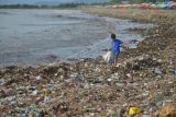 Seorang anak memilih barang yang masih bisa dimanfaatkan di antara tumpukan sampah di objek wisata Pantai Padang, Sumatera Barat, Selasa (15/11/2022). Tumpukan sampah pasca hujan lebat lima hari terakhir tersebut memenuhi kawasan pantai dan menimbulkan bau tidak sedap. ANTARA FOTO/Iggoy el Fitra/nz
