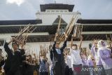Pelajar Sekolah Dasar memainkan alat musik angklung secara bersama di halaman Gedung Sate, Bandung, Jawa Barat, Minggu (20/11/2022). Gelaran yang diikuti ratusan peserta tersebut untuk memperingati Hari Angklung Dunia sekaligus perayaan 12 tahun alat musik khas Jawa Barat tersebut diakuin sebagai warisan budaya tak benda dari Unesco. ANTARA FOTO/Novrian Arbi/agr