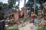Warga melintas di depan rumah yang roboh akibat gempa di Kampung Selakawung Tengah, Kabupaten Cianjur, Jawa Barat, Selasa (22/11/2022). Data dari BPBD Kabupaten Cianjur mencatat, hingga pukul 21.30 sebanyak 162 orang meninggal dunia, 326 warga luka-luka dan 13.784 warga mengungsi. ANTARA FOTO/Raisan Al Farisi/agr

