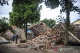 Warga melintas di depan rumah yang roboh akibat gempa di Kampung Selakawung Tengah, Kabupaten Cianjur, Jawa Barat, Selasa (22/11/2022). Data dari BPBD Kabupaten Cianjur mencatat, hingga pukul 21.30 sebanyak 162 orang meninggal dunia, 326 warga luka-luka dan 13.784 warga mengungsi. ANTARA FOTO/Raisan Al Farisi/agr
