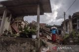 Warga membawa beras di dekat rumah yang rusak akibat gempa bumi di Gasol, Cianjur, Jawa Barat, Selasa (29/11/2022). Berdasarkan data dari BNPB, hingga hari selasa (29/11) gempa bumi Cianjur menyebabkan sebanyak 30.172 unit rumah mengalami rusak berat, 108.720 orang mengungsi dan 327 orang meninggal dunia. ANTARA FOTO/Novrian Arbi/agr