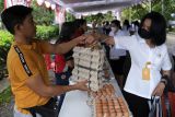 Pedagang menyerahkan telur kepada pembeli saat bazar pangan di Denpasar, Bali, Rabu (30/11/2022). Kegiatan yang digelar oleh Pemerintah Kota Denpasar tersebut untuk menekan laju inflasi dan membantu masyarakat memenuhi kebutuhan pangan pokok sehari-hari dengan harga yang terjangkau. ANTARA FOTO/Nyoman Hendra Wibowo/nym.