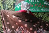 Warga menunjukkan kain batik saat peresmian Kampung Batik Orang Kranggan (Okra) di Jalan Kranggan VII, Surabaya, Jawa Timur, Rabu (28/12/2022). Batik tulis yang dijual dengan harga bervasriasi per lembarnya itu diproduksi oleh 25 orang dari masyarakat berpenghasilan rendah (MBR) di kampung tersebut. Antara Jatim/Didik Suhartono