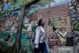 Warga melintas di dekat Mural Braga Tempo Dulu di kawasan Braga, Bandung, Jawa Barat, Rabu (28/12/2022).  Mural tersebut menjadi penghias sekaligus edukasi serta informasi tentang aktivitas sosial di kawasan Braga sejak jaman kolonial hingga saat ini. ANTARA FOTO/Novrian Arbi/agr