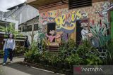 Warga melintas di dekat Mural Braga Tempo Dulu di kawasan Braga, Bandung, Jawa Barat, Rabu (28/12/2022). Mural tersebut menjadi penghias sekaligus edukasi serta informasi tentang aktivitas sosial di kawasan Braga sejak jaman kolonial hingga saat ini. ANTARA FOTO/Novrian Arbi/agr