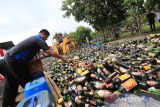Petugas menggunakan alat berat memusnahkan botol minuman keras hasil sitaan di Makopolres Indramayu, Jawa Barat, Rabu (28/12/2022). Sebanyak 19.500 botol Miras dimusnahkan jelang perayaan Tahun Baru 2023. ANTARA FOTO/Dedhez Anggara/agr