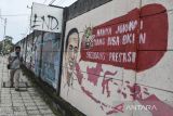 Warga melintas di dekat mural yang bertuliskan âhanya Jokowi yang bisa bikin segudang prestasiâ di Kabupaten Ciamis, Jawa Barat, Jumat  (30/12/2022). Mural tersebut merupakan wujud ekspresi dari warga sebagai bentukan dukungan dan apresiasi terhadap kinerja pemerintah di era Presiden Joko Widodo. ANTARA FOTO/Adeng Bustomi/agr