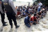 Personil Polri mengamankan sejumlah imigran etnis Rohingya terdampar di pantai desa Kampung Baru, Kecamatan Masjid Raya, Kabupaten Aceh, Besar, Aceh, Minggu (8/1/2023). Sebanyak 184 imigran etnis Rohingya terdiri dari sebanyak 69 laki laki dewasa, 75 perempuan dewasa, dan 40 anak anak terdampar di pantai Kabupaten Aceh Besar. ANTARA FOTO/Ampelsa/YU