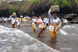 Umat Hindu melintasi ombak saat akan melaksanakan persembahyangan pada Hari Suci Siwaratri di Pura Tanah Lot, Tabanan, Bali, Jumat (20/1/2023). Persembahyangan di Pura yang berlokasi di tengah laut tersebut berjalan lancar dengan memperhitungkan pasang surutnya air laut. ANTARA FOTO/Nyoman Hendra Wibowo/wsj.
