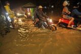 Sejumlah warga melintasi jalan yang terendam banjir di Kelurahan Rawa Makmur, Kecamatan Muara Bangkahulu, Kota Bengkulu, Provinsi Bengkulu, Senin (23/1/2023). Berdasarkan data dari Badan Penanggulangan Bencana Daerah (BPBD) Provinsi Bengkulu sebanyak 150 rumah di wilayah tersebut terendam banjir dan menyebabkan arus lalulintas jalan utama menjadi lumpuh total. ANTARA FOTO/Muhammad Izfaldi/Lmo/hp.