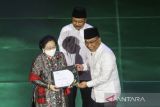 Presiden ke-5 RI Megawati Soekarnoputri (kiri) mewakili Presiden RI pertama Soekarno menerima penghargaan kategori nasional yang diberikan oleh Ketua PBNU KH Yahya Cholil Staquf (kanan) saat Anugerah Satu Abad NU di Theater Indonesia, TMII, Jakarta, Selasa (31/1/2023) malam. Pengurus Besar Nahdlatul Ulama (PBNU) menggelar malam Anugerah Satu Abad NU sebagai ajang pemberian penghargaan kepada pihak-pihak yang berjasa dalam membesarkan NU. ANTARA FOTO/Asprilla Dwi Adha/tom. 