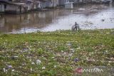 Seorang warga berjalan di atas tumpukan sampah yang menutup Sungai Martapura di Banjarmasin, Kalimantan Selatan, Rabu (1/2/2023). Sampah kiriman dalam dua hari terakhir dari hulu sungai akibat intensitas hujan yang tinggi tersebut menyebabkan arus lalu lintas transportasi sungai tersebut terganggu. Foto Antaranews Kalsel/Bayu Pratama S.