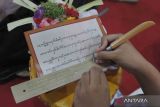Mahasiswa menulis aksara Bali di atas daun lontar saat peringatan ke-5 Bulan Bahasa Bali tahun 2023 di Taman Budaya Bali, Denpasar, Bali, Rabu (1/2/2023). Kegiatan yang digelar 1-28 Februari 2023 tersebut mengusung tema 