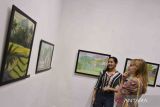 Pengunjung mengamati karya lukisan yang dipajang dalam pameran bertajuk 