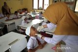 Petugas kesehatan memberikan vaksin polio tetes (Oral Poliomyelitis Vaccine) tahap dua kepada pelajar  di Sekolah Dasar Negeri 7, Banda Aceh, Aceh, Kamis (13/2/2023). Pemerintah provinsi Aceh menggelar vaksin polio tahap dua secara serentak di sejumlah kabupaten/kota  dengan target capaian sebanyak 1,2 juta anak pada tahaun 2023. ANTARA FOTO/Ampelsa.