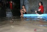 Warga berada di rumahnya yang terendam banjir di Kepatihan, Banyuwangi, Jawa Timur, Jumat (10/2/2023). Hujan deras yang mengguyur selama 3 jam di daerah tersebut mengakibatkan debit air Sungai Kalilo meluap dan menggenangi pemukiman warga yang tinggal di bantaran sungai. ANTARA Jatim/Budi Candra Setya/zk