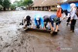 Sejumlah warga bersama relawan membersihkan material lumpur yang terbawa banjir di halaman SDN Sempol 1, Bondowoso, Jawa Timur, Senin (13/2/2023). Banjir bandang yang terjadi pada Minggu (12/2) malam itu merendam sekolahan tersebut sehingga proses belajar mengajar diliburkan sementara. ANTARA Jatim/Budi Candra Setya/zk