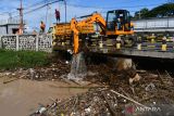 Petugas Badan Penanggulangan Bencana Daerah (BPBD) menggunakan alat berat mengangkat sampah yang menyangkut di tiang jembatan Sungai Piring Kota Madiun, Jawa Timur, Senin (13/2/2023). Pembersihan sampah yang terbawa air saat banjir dari darerah hulu dan menyangkut di pilar jembatan tersebut dimaksudkan untuk mitigasi bencana. ANTARA Jatim/Siswowidodo/zk